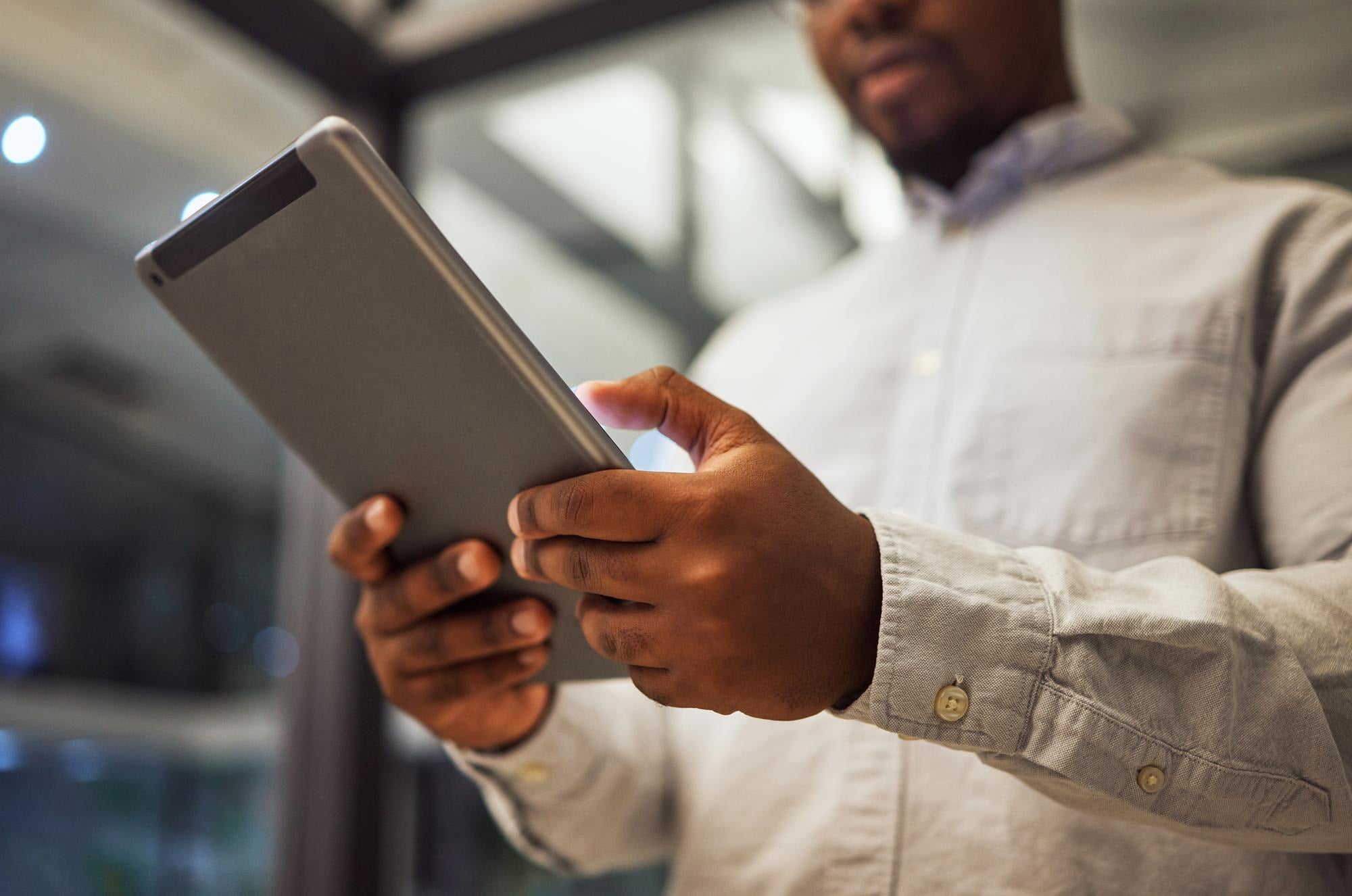 A manager holding a tablet in an office building at dusk